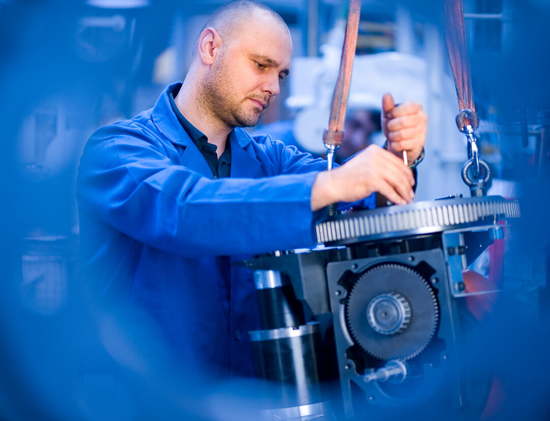 Ein Mann montiert im Blaumann an einem Elektromotor.